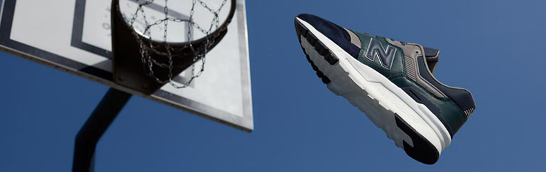 Een blauwe New Balance 997 sneaker die in een basket wordt gegooid